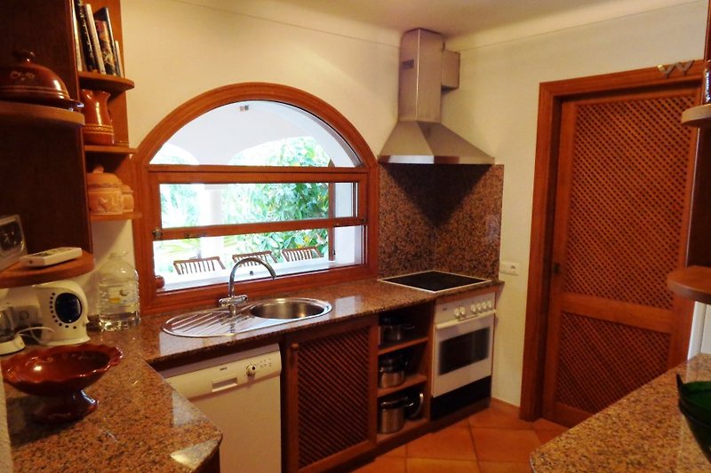 Voll ausgestattete Küche mit Durchreiche zur überdachten Terrasse. 