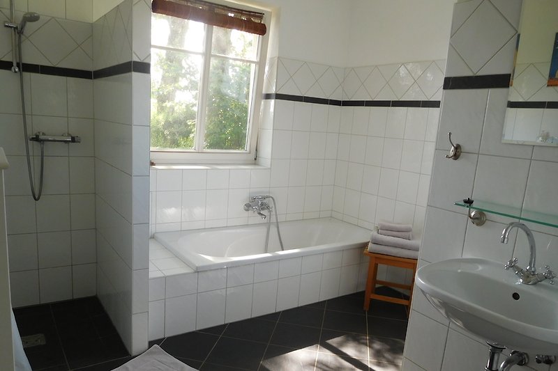 De badkamer met inloopdouche en badkuip