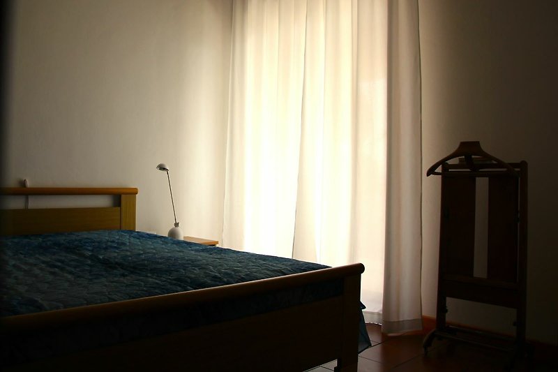OG: Schlafzimmer mit stilvoller Beleuchtung und Holzmöbeln. Gemütliches Bett mit hochwertiger Bettwäsche.