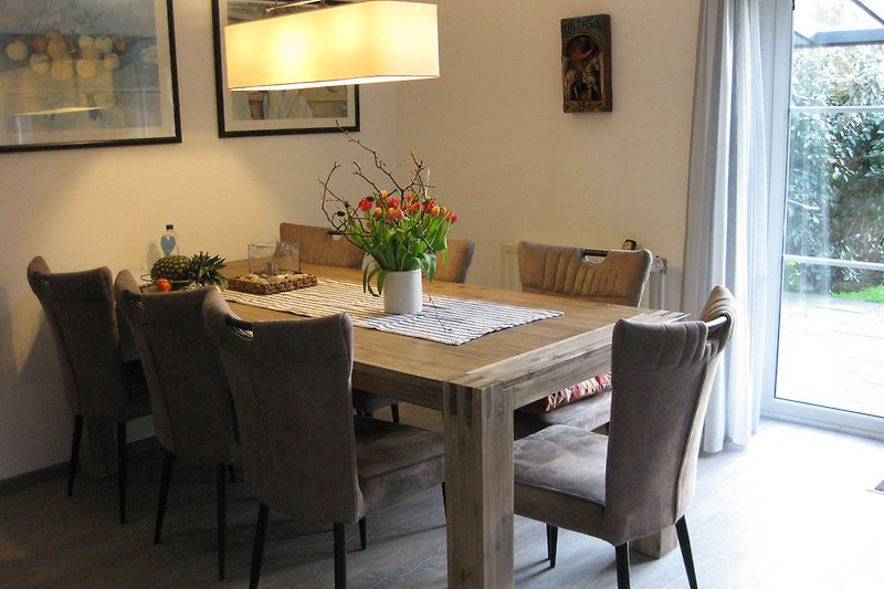 2.20 m dining table with comfortable chairs, on the right the French door leading to the terrace.