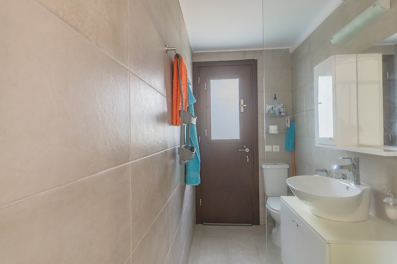 Gemütliches Badezimmer mit Spiegel, Waschbecken und modernen Armaturen.