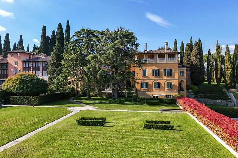 Prächtige Villa mit weitläufigem Garten, Zypressen und gepflegtem Rasen.