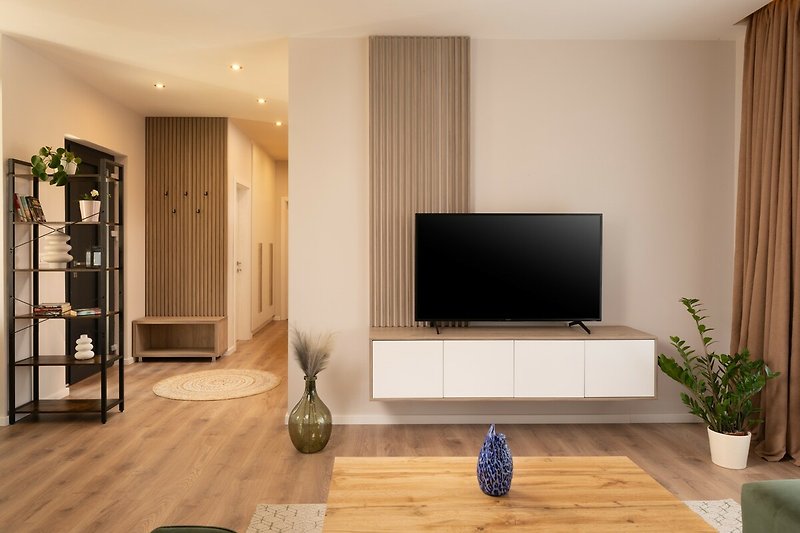 Wohnzimmer mit moderner Einrichtung und Fernseher.