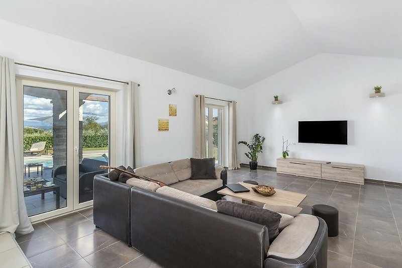Stilvolles Wohnzimmer mit grauem Sofa, Holztisch und Fernseher.