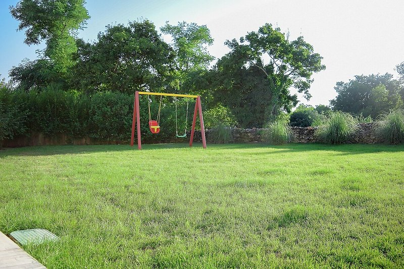 A beautiful landscape with lush green grass, trees, and a soccer goal in a spacious yard.