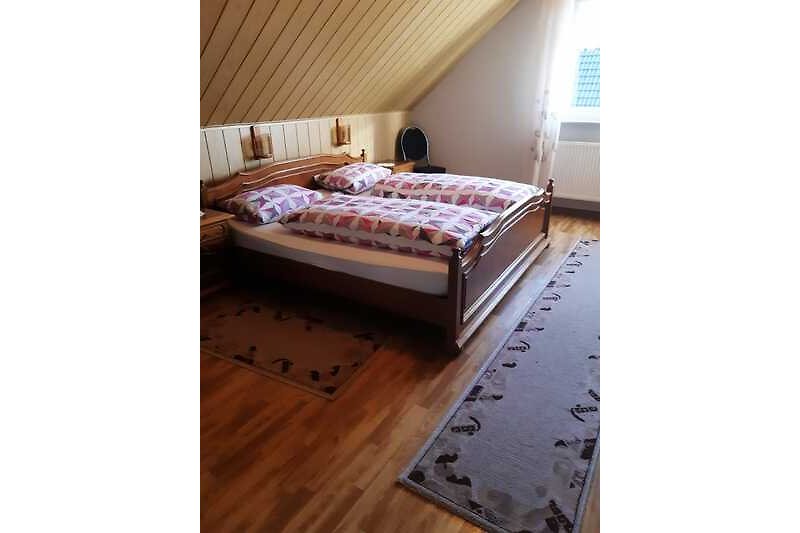 Großes Schlafzimmer mit Doppelbett sowie Kinderbett