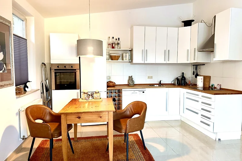 Offene Küche mit Holzfronten, Granitplatte, Esstisch und Designerleuchten.