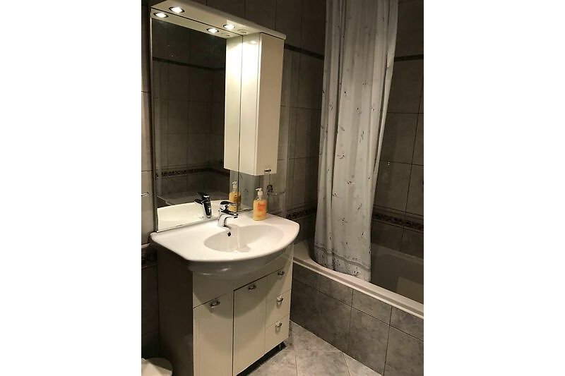 Modernes Badezimmer mit Spiegel, Waschbecken und Armaturen.