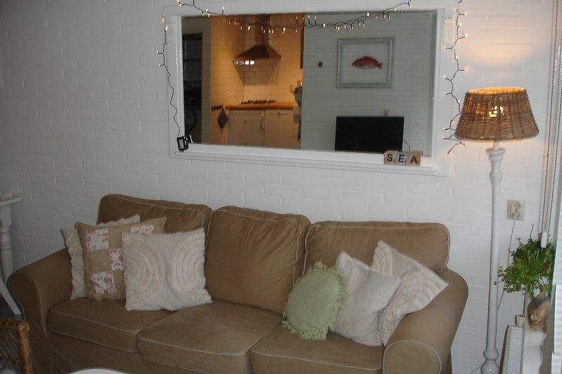 Gemütliches Wohnzimmer mit brauner Couch, weißem Licht und Pflanzen.