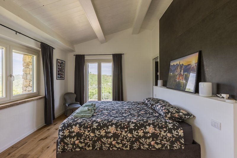Gemütliches Schlafzimmer mit Holzbett, Fensterblick und Nachttisch.