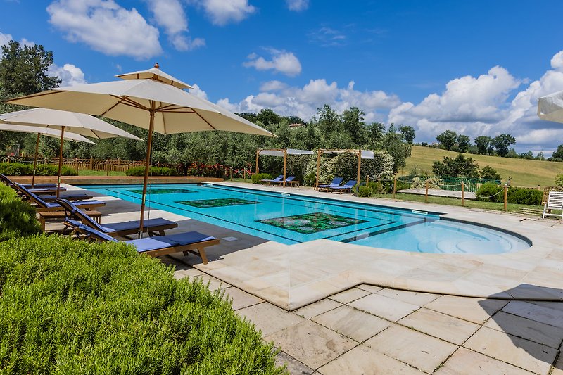 Una proprietà con piscina, mobili da esterno e ombrelloni, circondata da una bellissima vista panoramica.