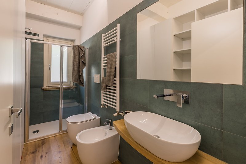 Badezimmer mit Spiegel, Waschbecken und Fliesenwand.