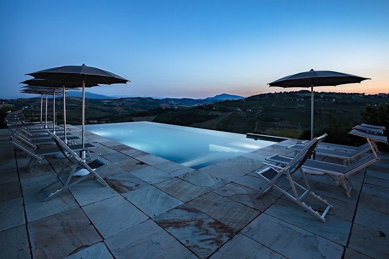 Una vista panoramica sulla piscina e il paesaggio circostante con mobili da esterno.