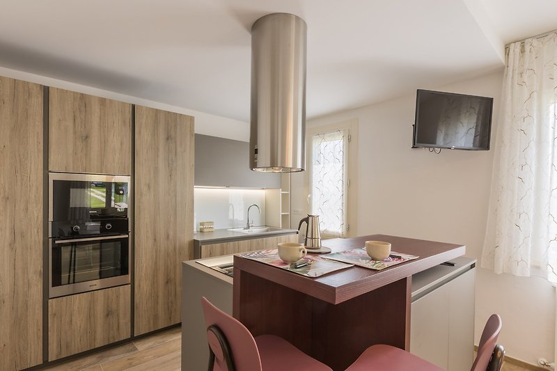 Una cucina con mobili in legno, piano di lavoro e finestra luminosa.