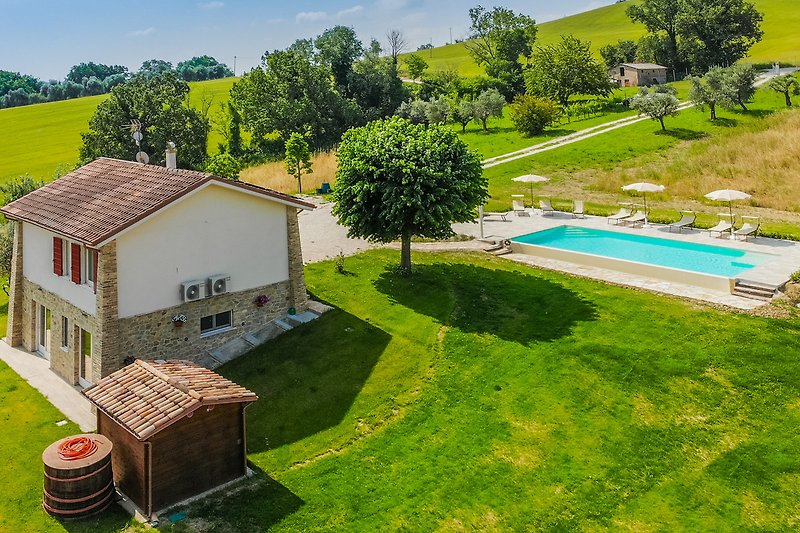 Una casa con piscina, prato verde e mobili da esterno. Goditi una vacanza rilassante all'aria aperta!