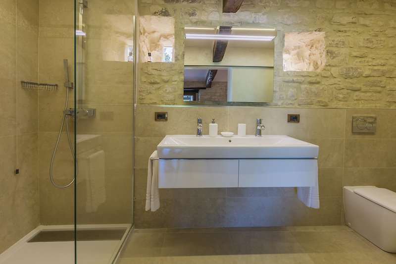 Un bagno moderno con lavabo, specchio e doccia.