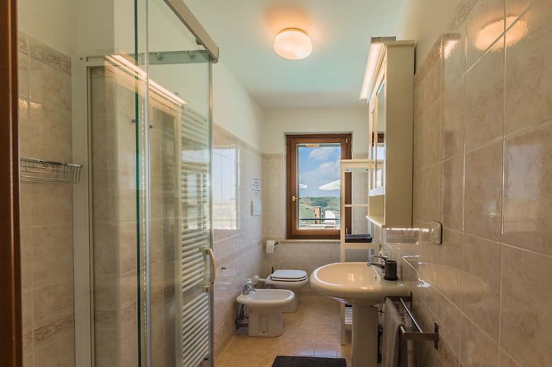 Modernes Badezimmer mit Dusche, Spiegel und Fenster.