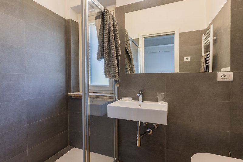 Badezimmer mit Spiegel, Waschbecken und Fliesenwand.