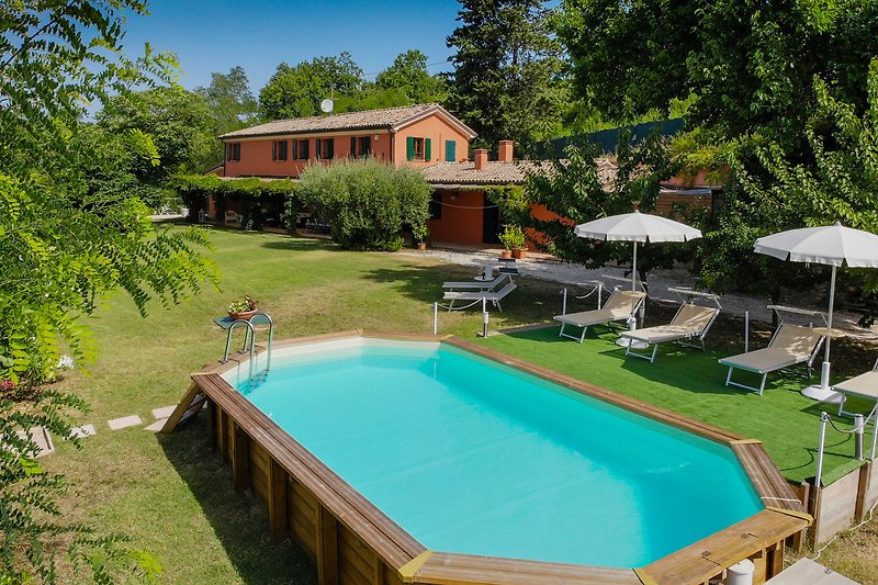 Una propiedad con piscina y vistas al mar, rodeada de naturaleza y con mobiliario exterior.
