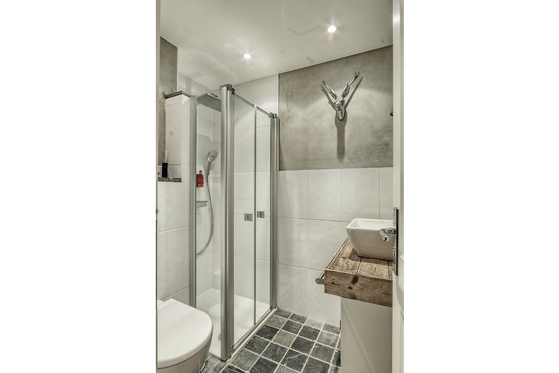 Moderne Badezimmerausstattung mit Glasdusche und Metallarmatur.