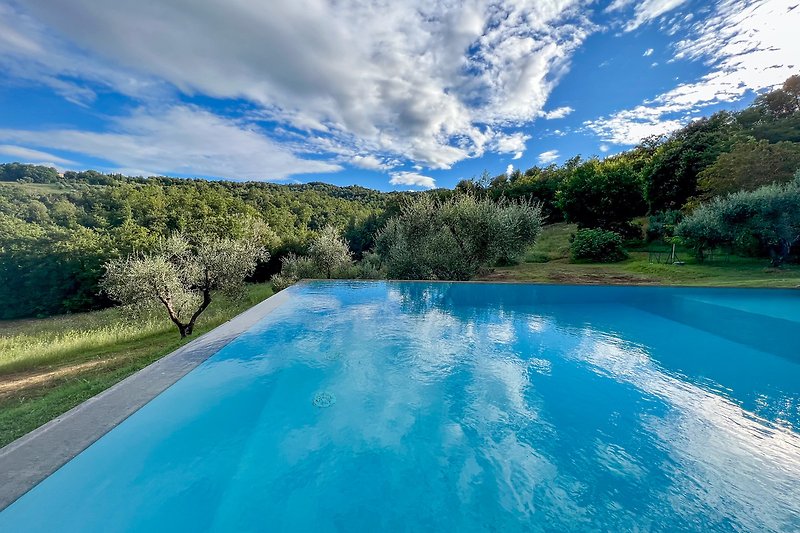 Affitto di una casa con piscina, vista panoramica sulla natura e nuvole bianche.