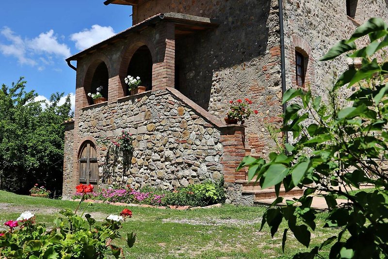 Una casa di campagna con un giardino fiorito e un'architettura medievale.