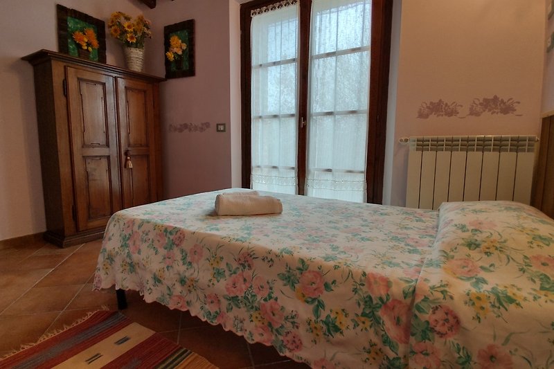 Una camera da letto accogliente con arredamento in legno e tessuti, finestra con tende e un letto comodo.