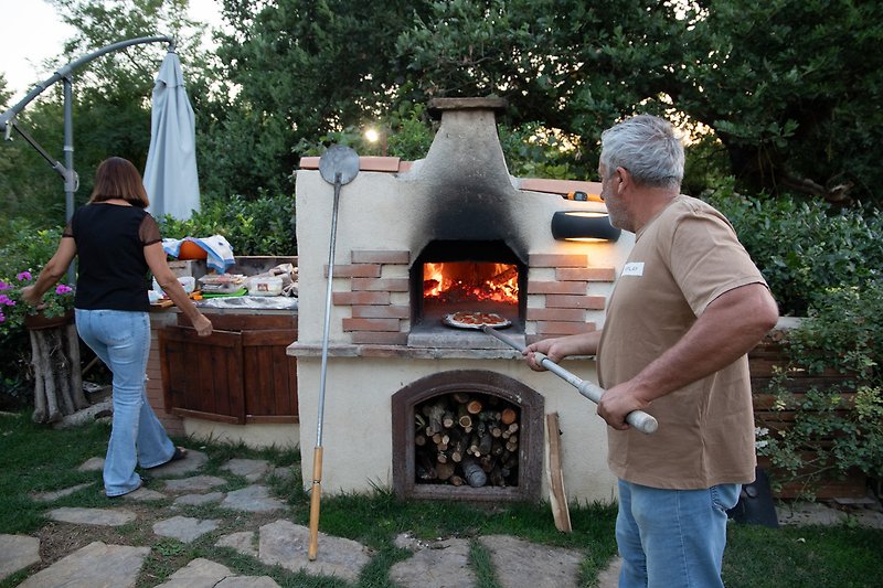 Una cucina all'aperto con un forno a legna e un barbecue.