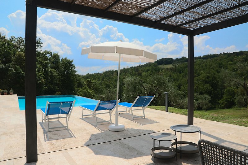 Una piscina con mobili da esterno e vista panoramica sulla natura.