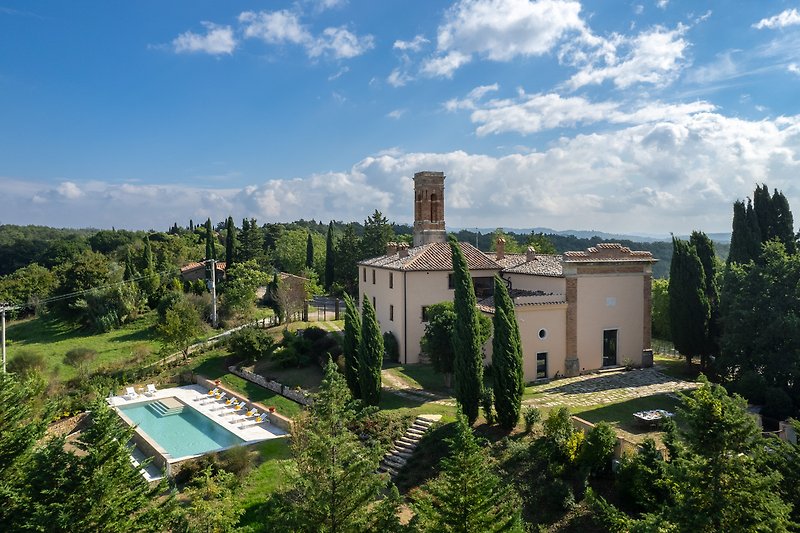 Luxuriöse Villa mit Pool, umgeben von Grün und Palmen.