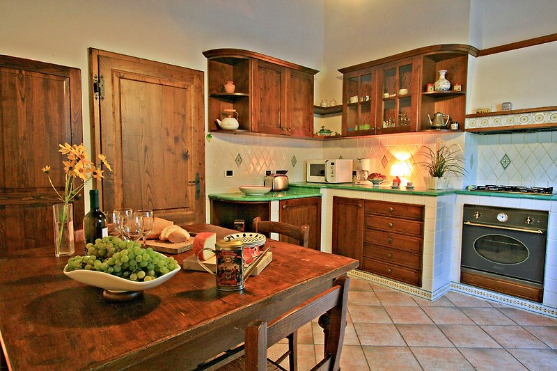 Una cucina con mobili in legno, piano di lavoro e illuminazione.