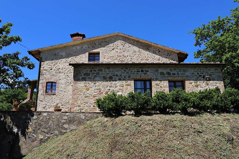 Una casa di campagna con un tetto in pietra e una finestra affacciata sul paesaggio.