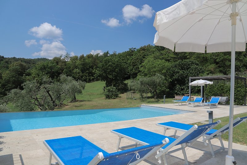 Una piscina con mobili da esterno e vista panoramica sulla natura.