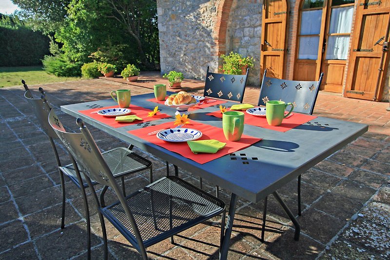 Una tavola all'aperto con sedie, piante e fiori.