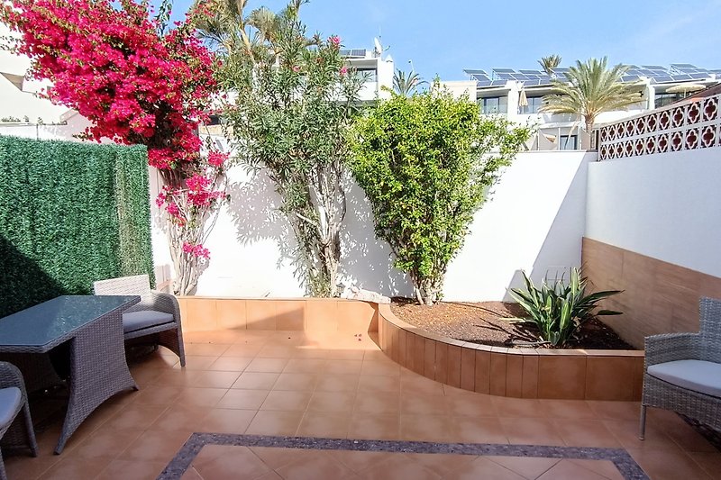 Gartenidylle mit blühenden Pflanzen, gemütlicher Terrasse und malerischem Hintergrund.