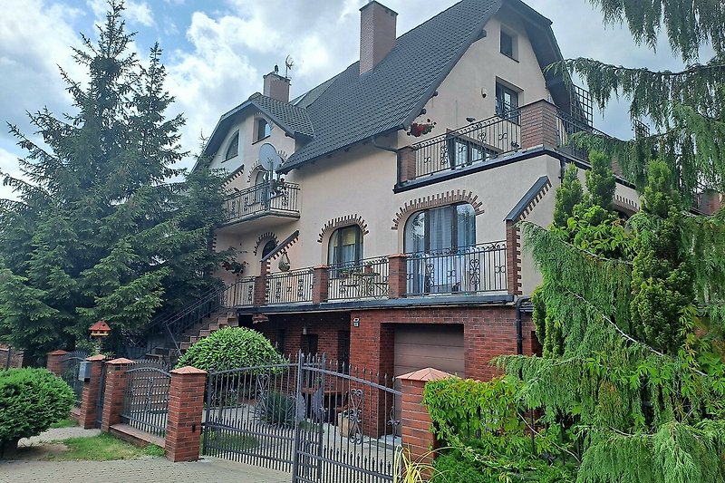 Charmantes Landhaus mit Garten, Bäumen und klassischer Architektur.