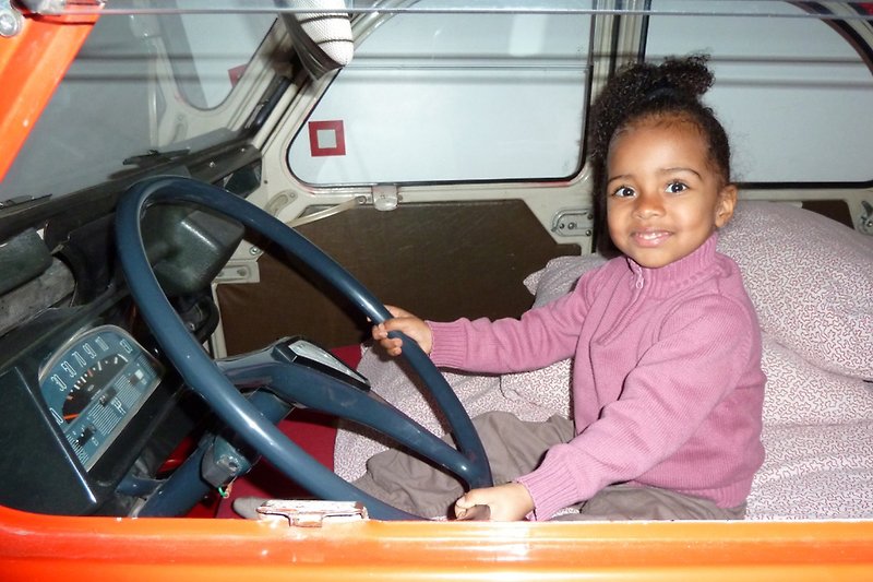 Ein lächelndes Kind im Auto mit Lenkrad
