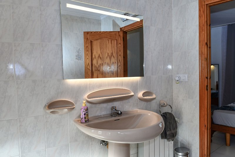 Modernes Badezimmer mit Holzmöbeln und Spiegel.