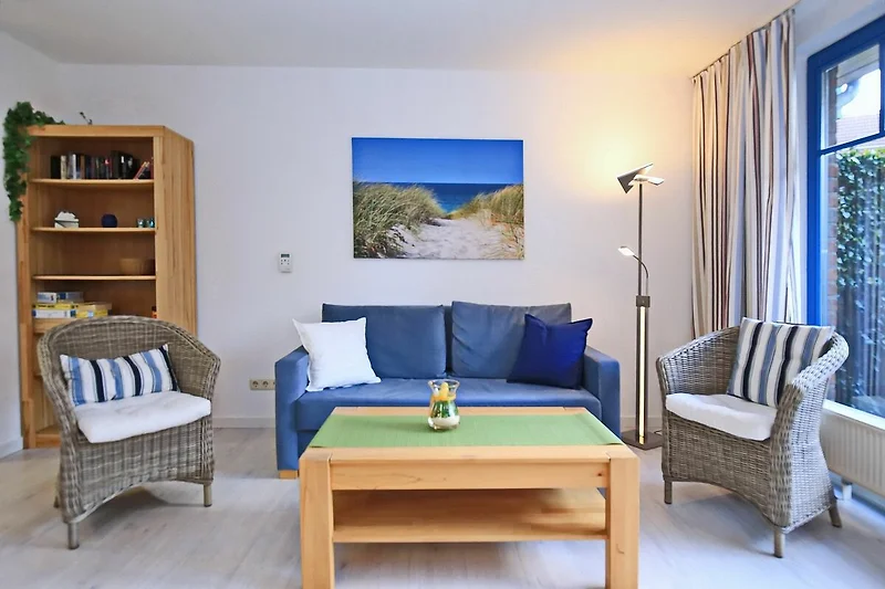 Wohnzimmer mit Schlafcouch und Korbsesseln