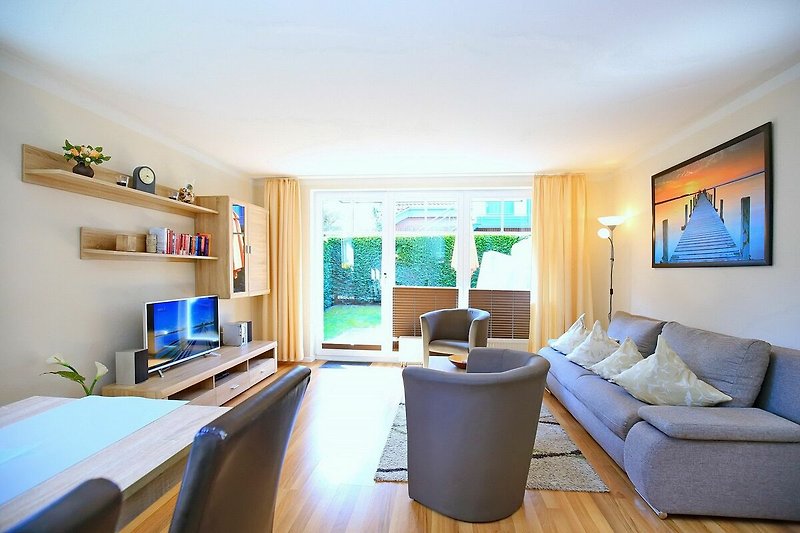 Wohnzimmer mit Schlafcouch, TV, Esstisch und Blick zur Terrasse