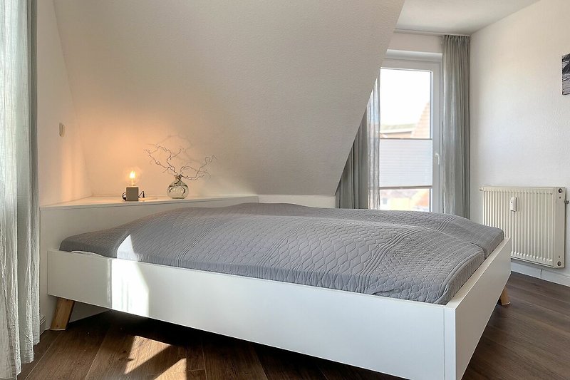 Doppelbett im ersten Schlafzimmer mit Zugang zum Balkon