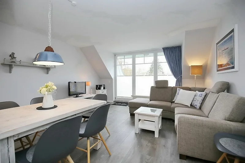 Wohnzimmer mit Sofaecke, TV, Esstisch und Blick zum Balkon