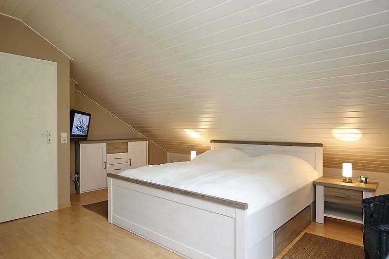 zweites Schlafzimmer mit Doppelbett, Kommode und TV