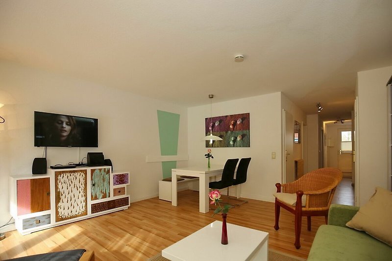 Wohnzimmer mit Essbereich, TV, Korbsessel und Blick zum Eingangsbereich