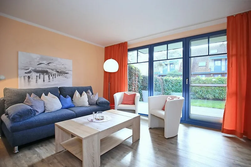 Wohnzimmer mit Schlafcouch und Sesseln mit Blick zur Terrasse