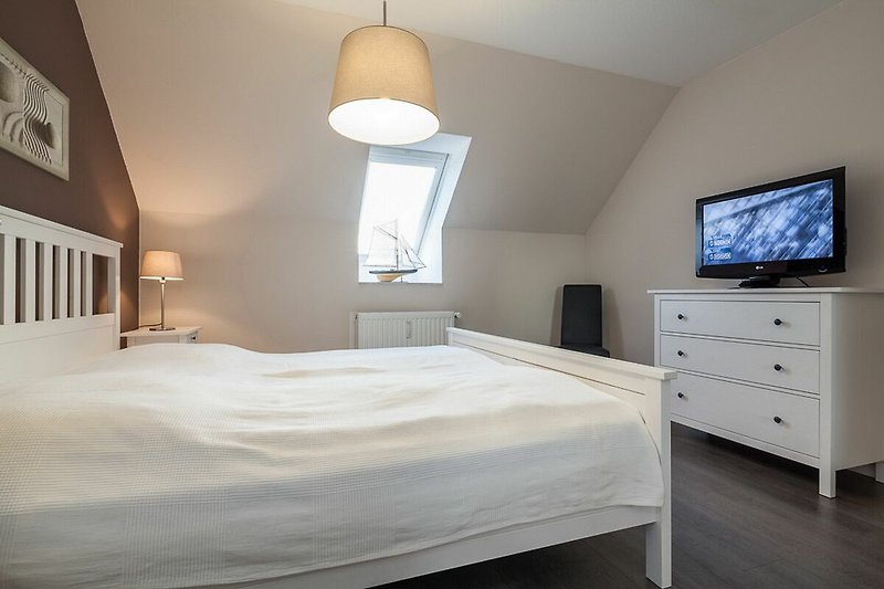 Schlafzimmer mit Doppelbett, Kommode und TV