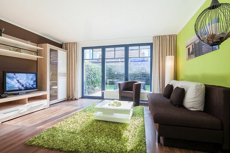 Wohnzimmer mit Schlafcouch, TV und Blick zur Terrasse