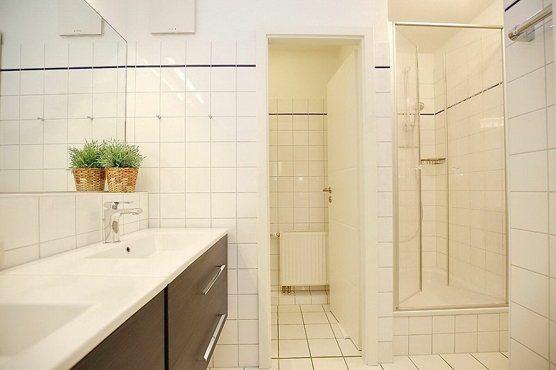 Badezimmer mit doppeltem Waschbecken, separatem WC und Dusche