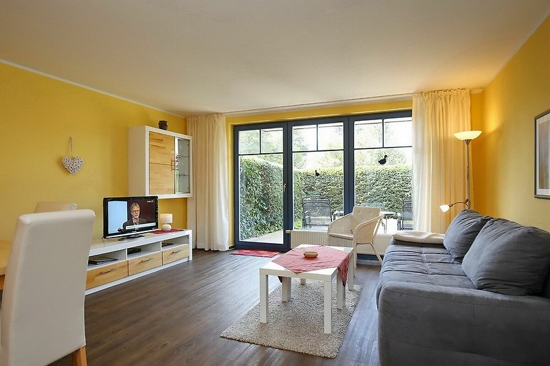 Wohnzimmer mit Schlafcouch, TV und Blick auf die Terrasse