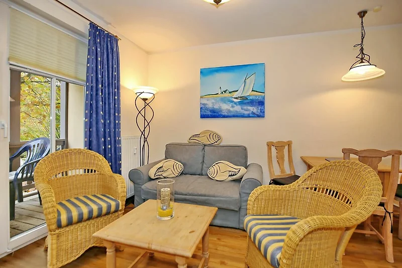 Wohnzimmer mit Schlafcouch und Korbsesseln